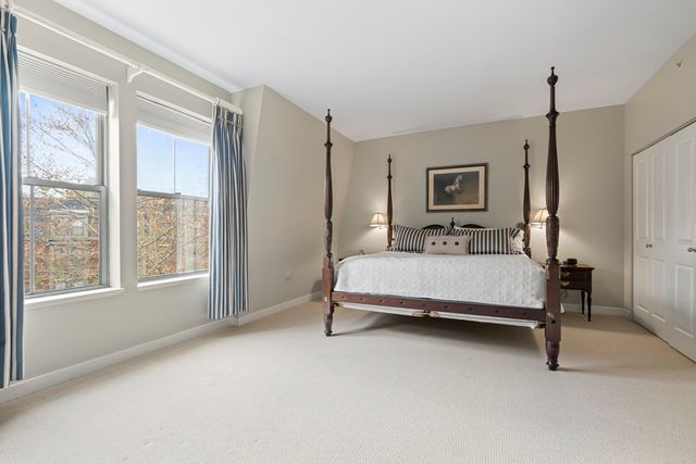 a bedroom with a bed a mirror and a large window