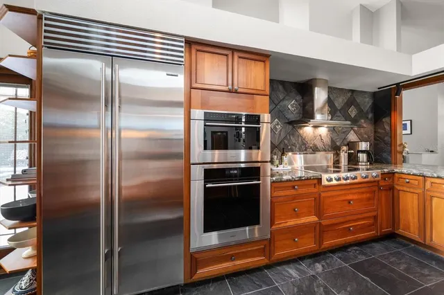 a kitchen with stainless steel appliances granite countertop a table chairs and a refrigerator