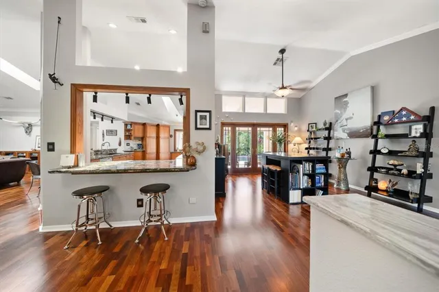 a living room with stainless steel appliances kitchen island granite countertop lots of wooden furniture and a large window