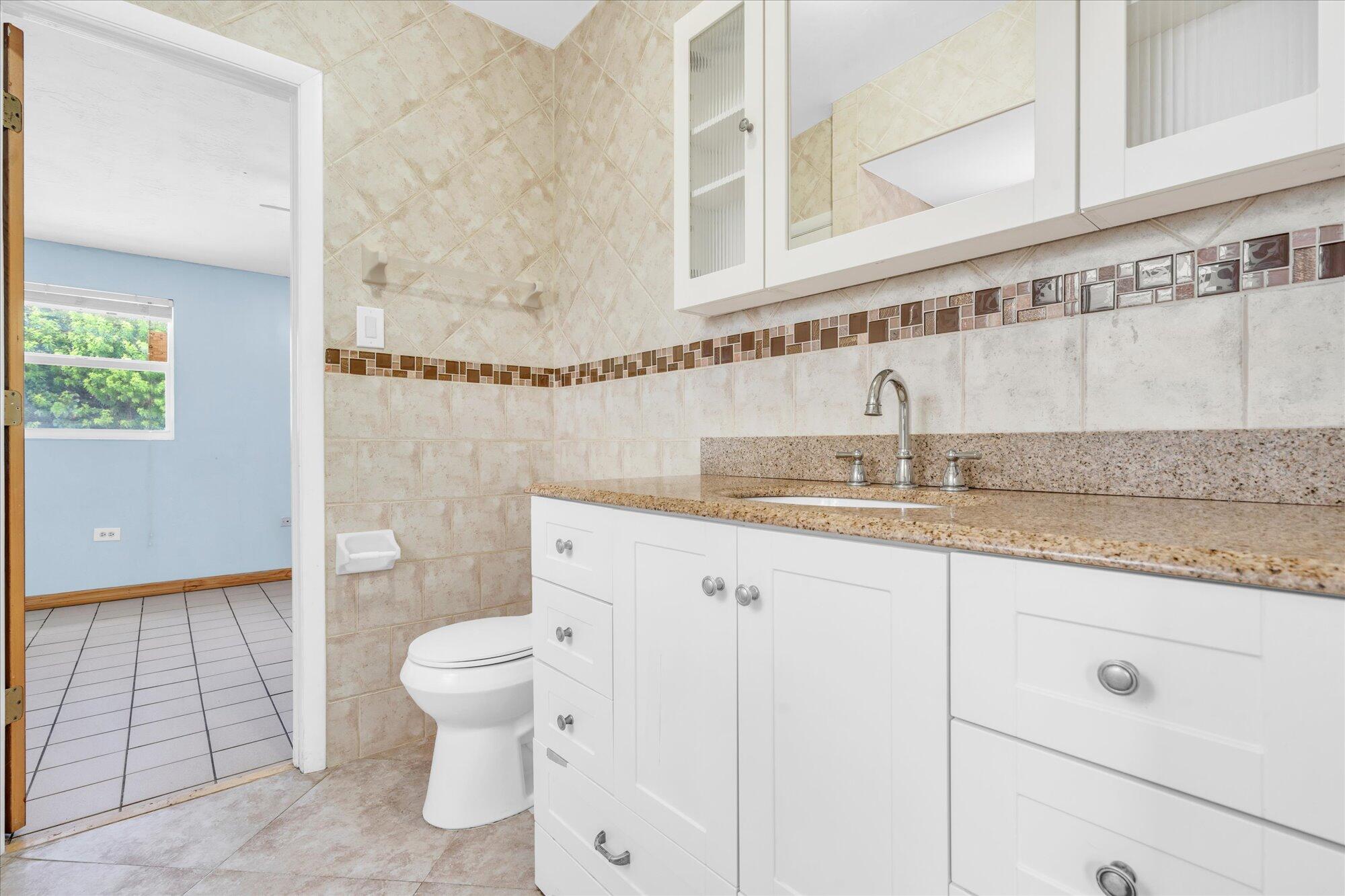 7984 Tuna Drive Marathon, FL 33050 - Photo 23 of 40 a bathroom with a granite countertop sink a toilet and a mirror