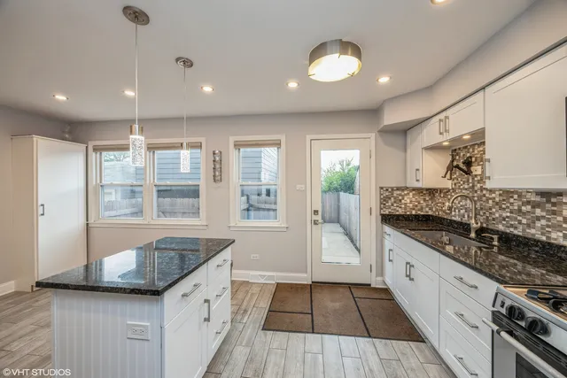 a large white kitchen with granite countertop a stove and a sink