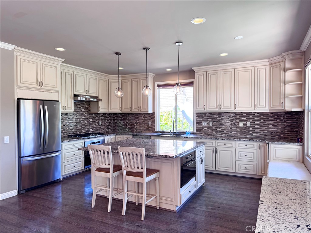 28463 Cascade Road Castaic, CA 91384 - Photo 7 of 29 a kitchen with stainless steel appliances granite countertop a stove a refrigerator a sink a oven with white cabinets and wooden floor