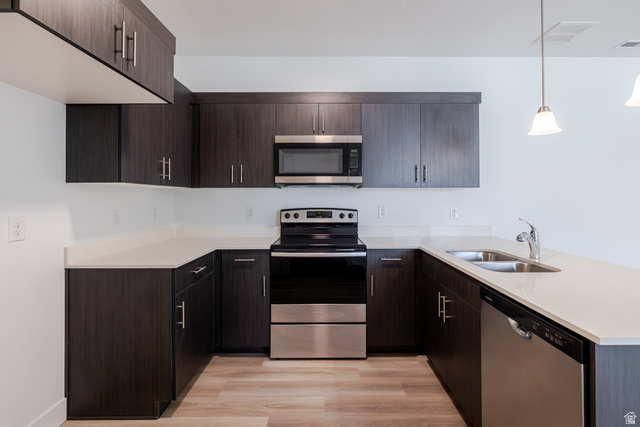 675 West 4500th South, Unit P201 Mapleton, UT 84664 - Photo 11 of 16 U-shaped kitchen with dark wood-finish cabinetry, light-toned countertops, and stainless steel appliances