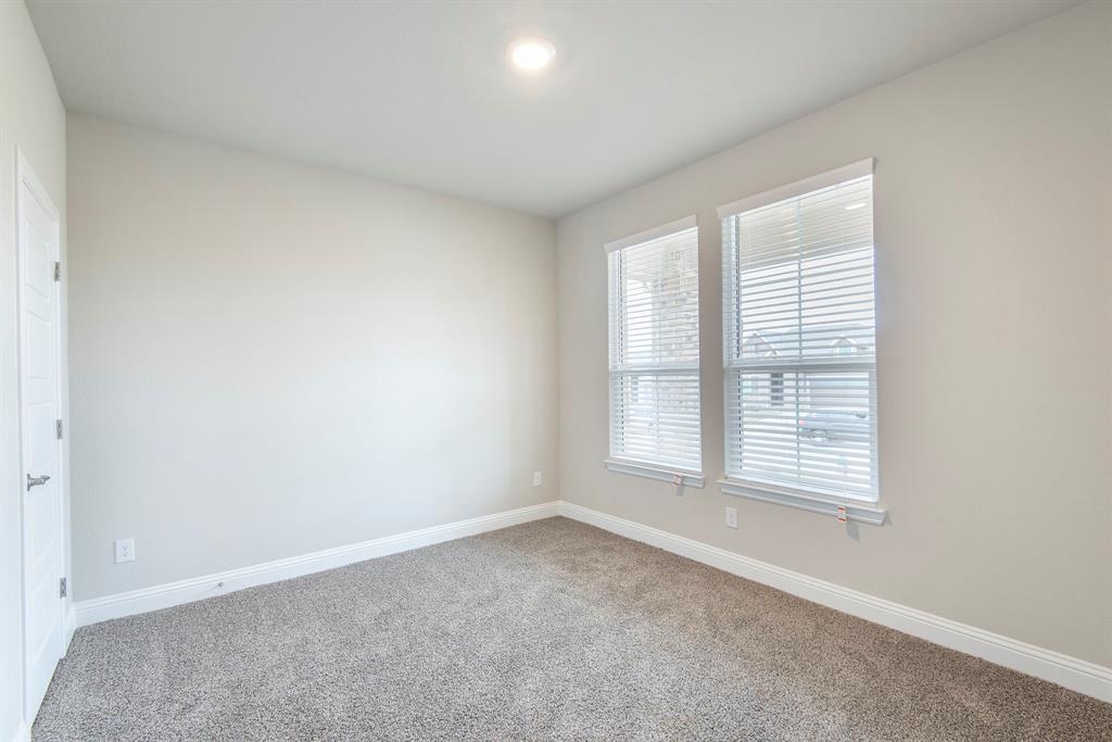 2301 Ruff Road Denton, TX 76205 - Photo 19 of 23 Room featuring soft gray wall paint, two windows with blinds, a white paneled door, and neutral carpet flooring