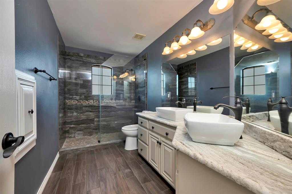 5520 White Settlement Road Weatherford, TX 76087 - Photo 37 of 40 a bathroom with a double vanity sink a toilet a mirror and shower