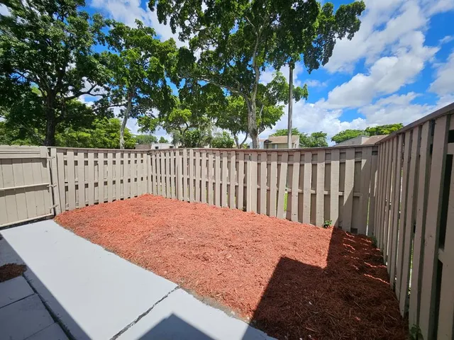a view of a house with a small yard plants and a large tree