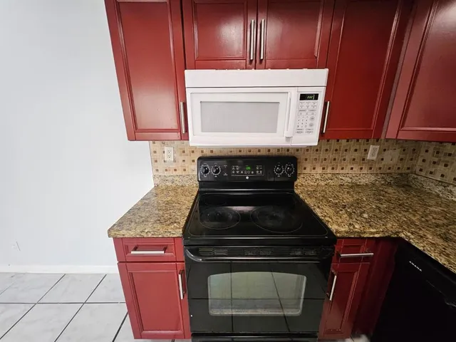 a kitchen with granite countertop wood cabinets and a stove top oven