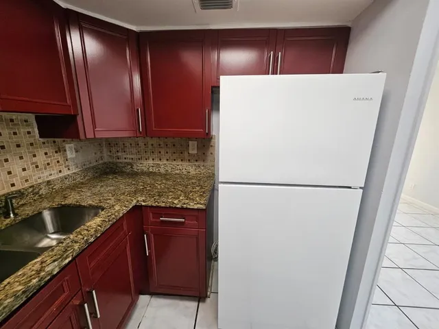 a view of kitchen with refrigerator and cabinets