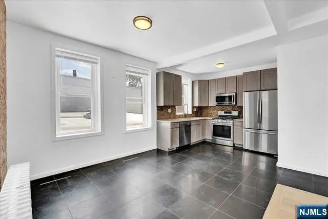 a kitchen with granite countertop a refrigerator a sink a stove and white cabinets