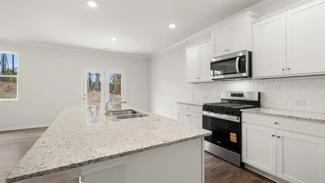 a kitchen with stainless steel appliances granite countertop a sink stove and microwave