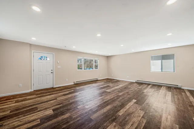 a view of an empty room with wooden floor and a window