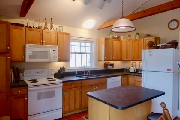a kitchen with a stove a sink a refrigerator and chairs