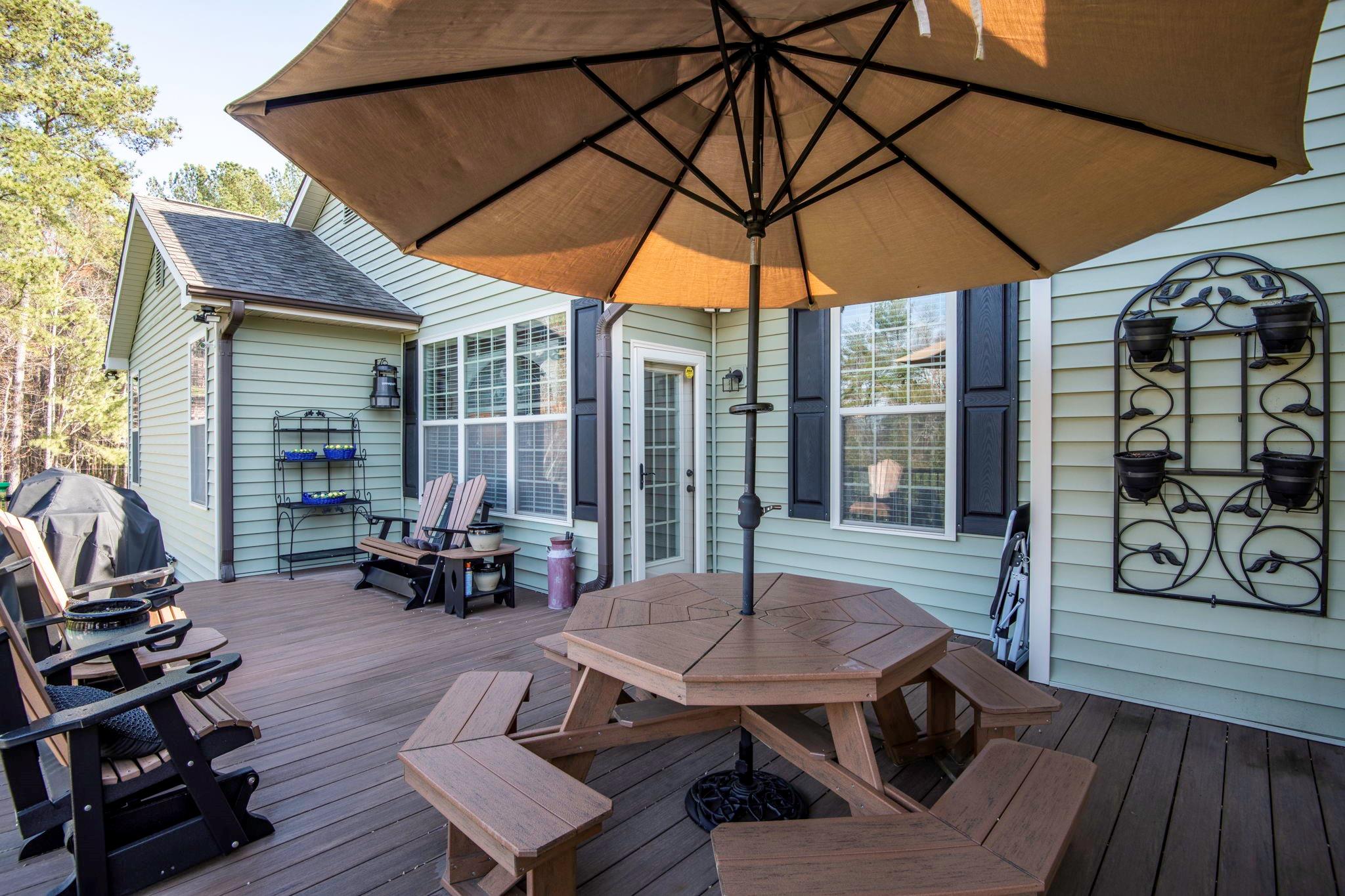 101 Ridge Top Drive Connelly Springs, NC 28612 - Photo 34 of 47 a view of a patio with table and chairs under an umbrella with wooden floor
