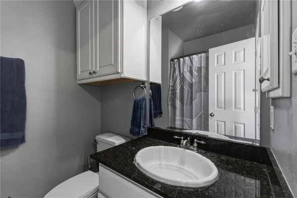 a bathroom with a granite countertop toilet sink and mirror