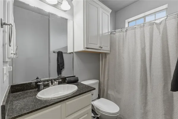 a bathroom with a granite countertop sink vanity mirror and toilet