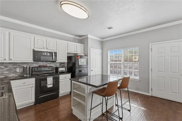 a kitchen with granite countertop a stove cabinets and wooden floor
