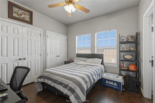 a bedroom with a bed a chair and potted plant on the dresser