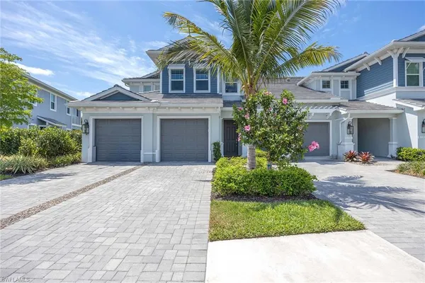 a front view of a house with a garden and palm trees