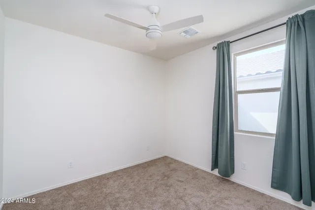 an empty room with a window and a ceiling fan