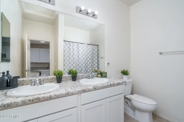 a bathroom with a granite countertop toilet sink and mirror