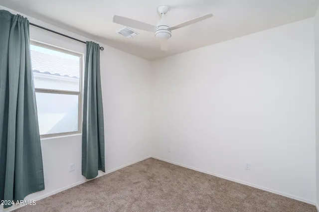 an empty room with a window and a fan