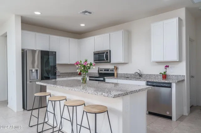a kitchen with kitchen island granite countertop a sink stove and refrigerator
