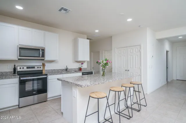 a kitchen with stainless steel appliances granite countertop a stove a sink a microwave a dining table and chairs