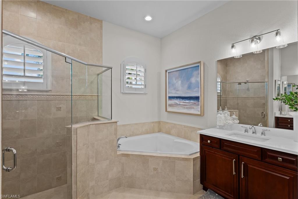 9774 Nickel Ridge Circle Naples, FL 34120 - Photo 16 of 50 a bathroom with a tub a sink and mirror