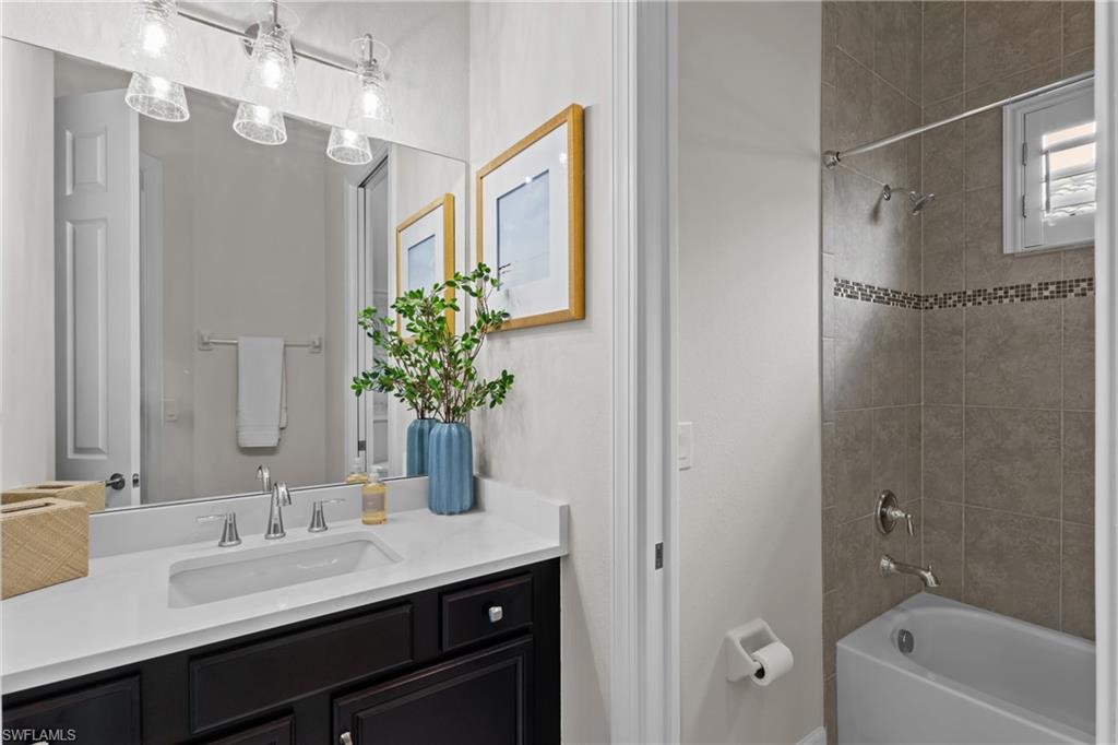9774 Nickel Ridge Circle Naples, FL 34120 - Photo 20 of 50 a bathroom with a granite countertop sink a large mirror a bathtub and shower