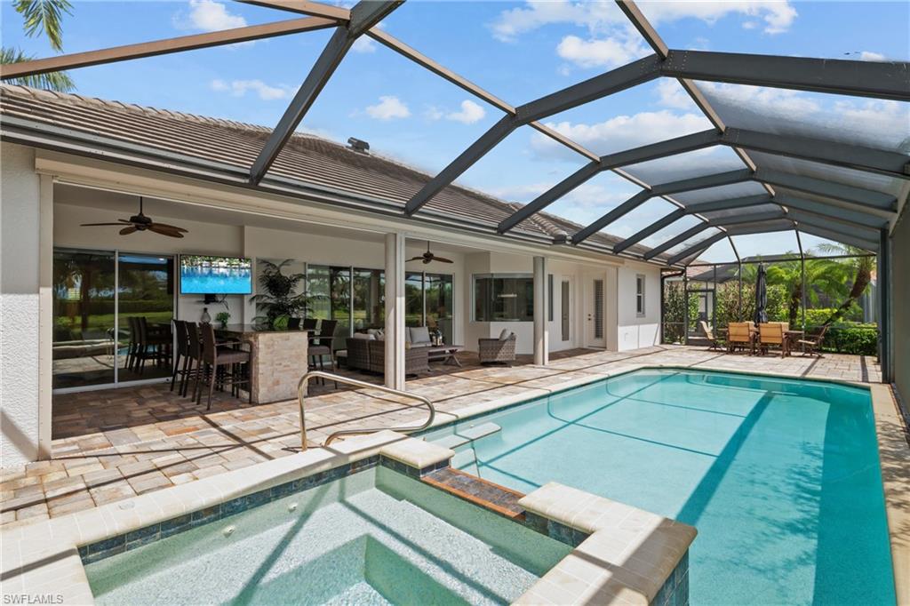9774 Nickel Ridge Circle Naples, FL 34120 - Photo 31 of 50 a view of a patio with a table and chairs under an umbrella next to a yard
