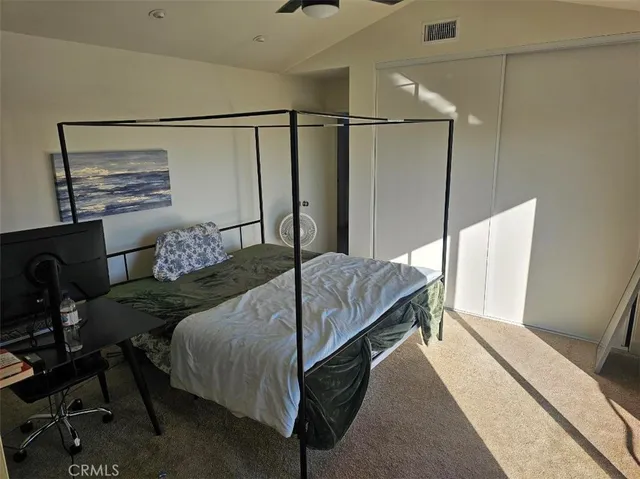 a bedroom with a bed a desk and chair with the wooden floor