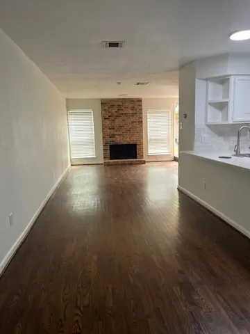 an empty room with wooden floor a fireplace and windows