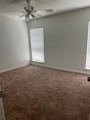 an empty room with a window and a fan