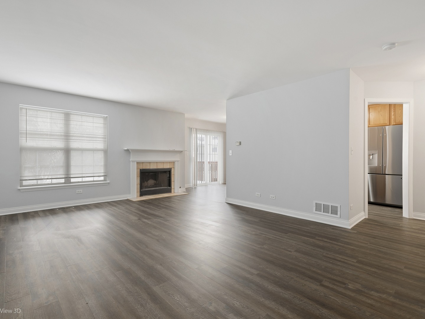 67 Colonial Court Streamwood, IL 60107 - Photo 2 of 25 an empty room with wooden floor fireplace and windows