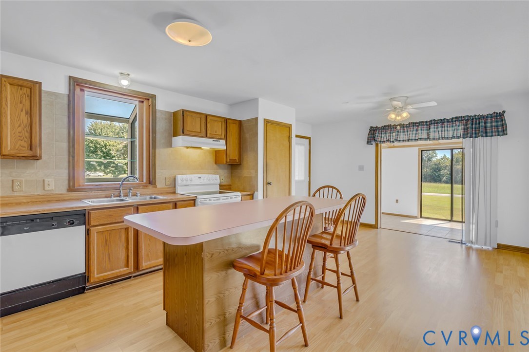 831 Fountain Gate Road Heathsville, VA 22473 - Photo 18 of 50 a dining hall with granite countertop a stove a sink a dining table and chairs with wooden floor