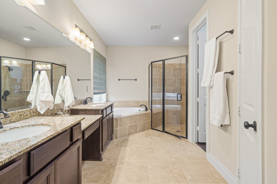 1607 Quail Ridge Drive Katy, TX 77493 - Photo 18 of 33 Indulge in the spaciousness of this primary bathroom featuring dual vanities, a large walk-in shower with mud-set tile, a frameless glass surround and a bright window that fill the space with natural light.