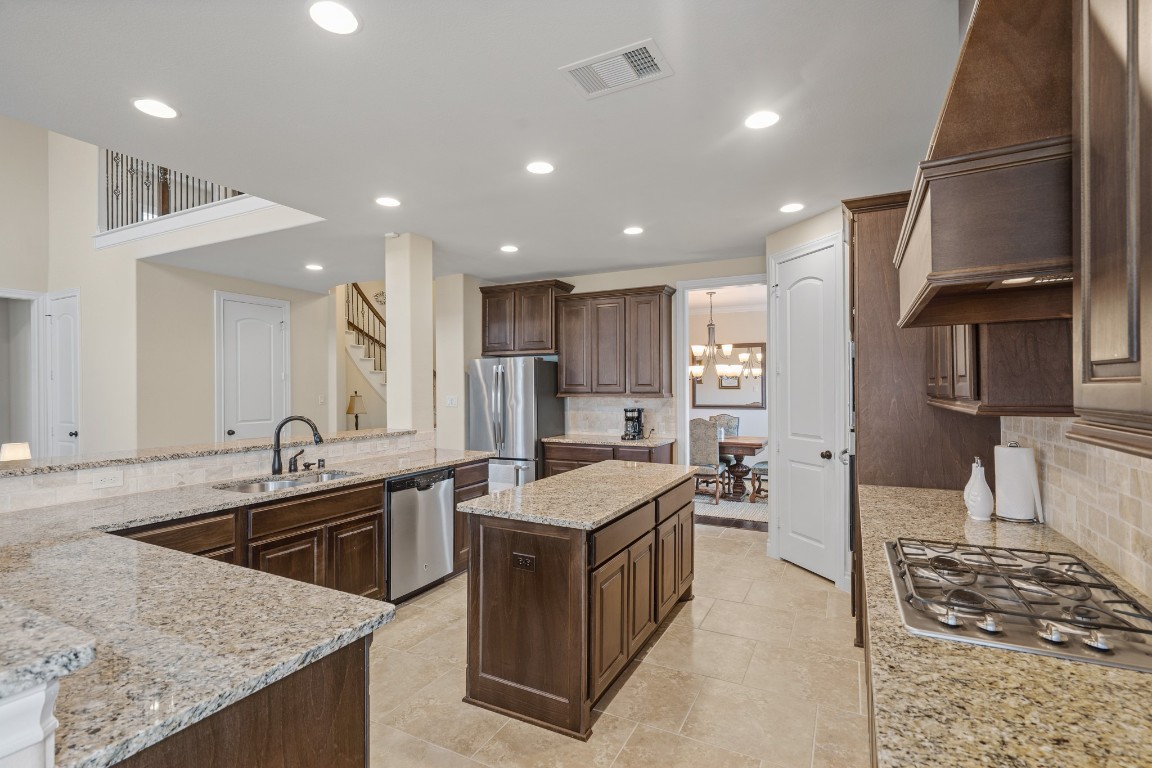 1607 Quail Ridge Drive Katy, TX 77493 - Photo 7 of 33 The open-concept kitchen opens up to the living area filled with natural light, featuring a large island with granite countertops, double sink, and recessed lighting. Seamlessly connected to the dining and living spaces, this layout is perfect for everyday living and entertaining.