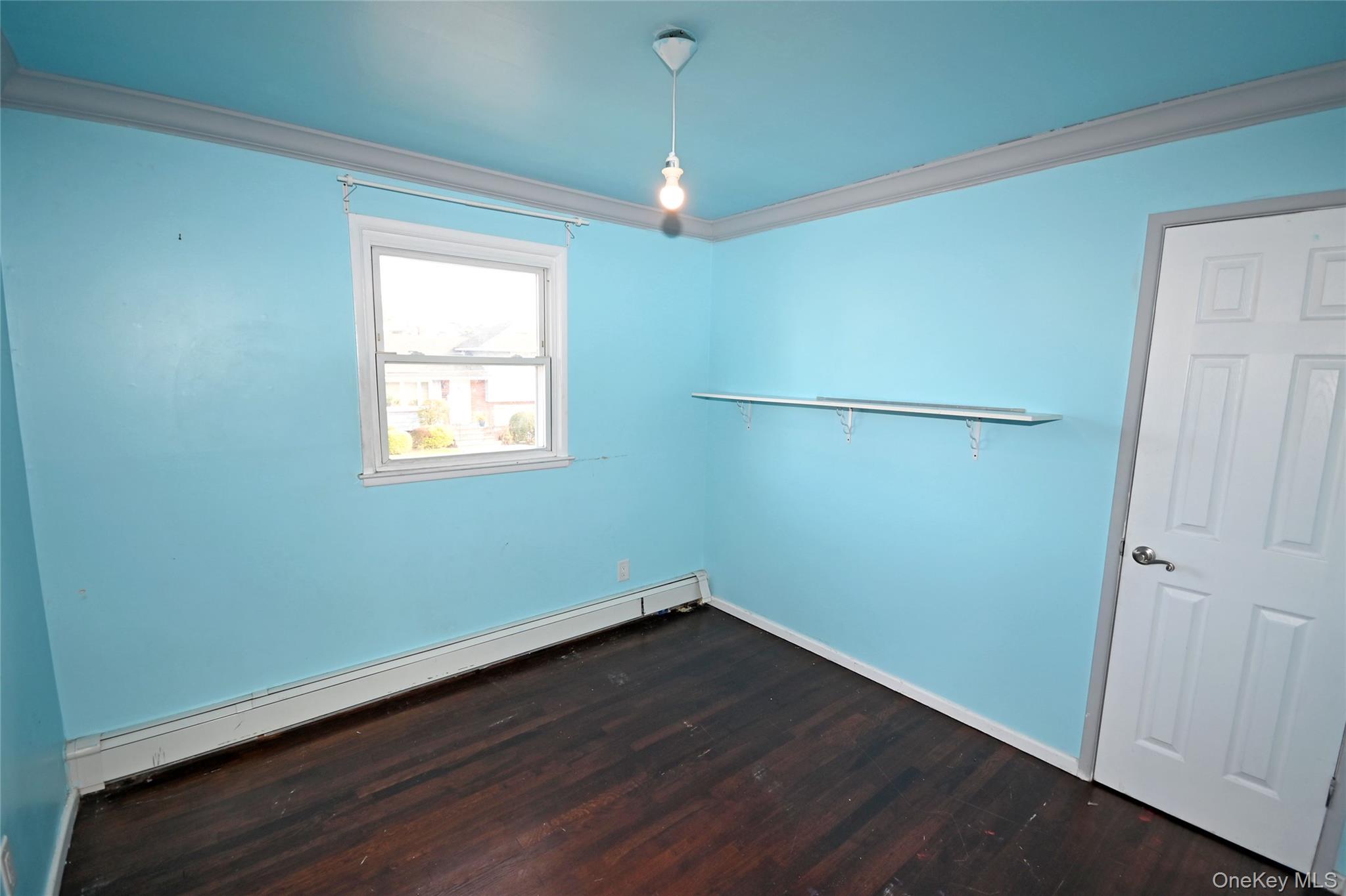 89 Osborne Road West Hempstead, NY 11552 - Photo 6 of 50 Unfurnished room with crown molding, a baseboard radiator, and dark wood-style floors