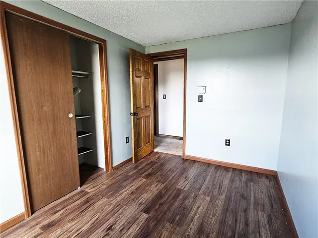 a view of an empty room with wooden floor and a fireplace