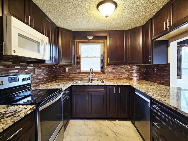 a kitchen with stainless steel appliances granite countertop wooden cabinets and a stove top oven