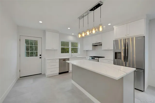 a large kitchen with kitchen island a sink stainless steel appliances and cabinets