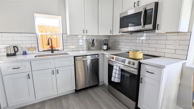 a kitchen with stainless steel appliances granite countertop white cabinets a sink and a microwave