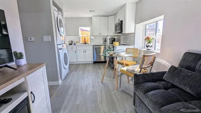 a living room with stainless steel appliances furniture and a wooden floor