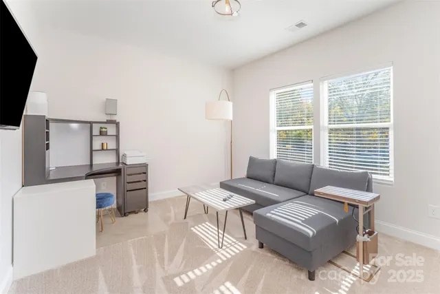 a living room with furniture a flat screen tv and a window