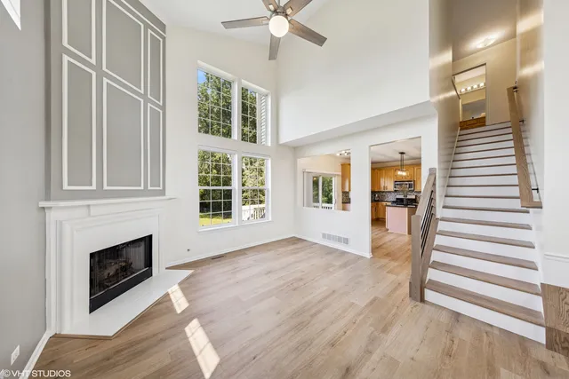 a view of a livingroom with wooden floor a ceiling fan and windows