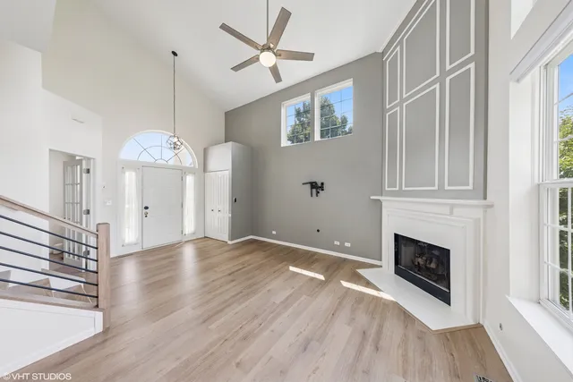 a view of an empty room with chandelier fan and fire place