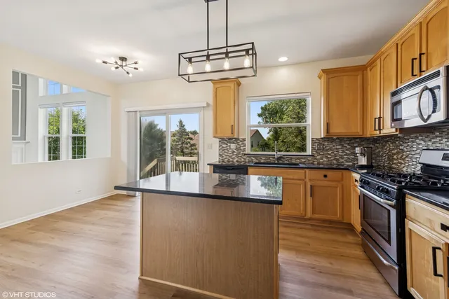 a kitchen with stainless steel appliances granite countertop a stove and a wooden floors
