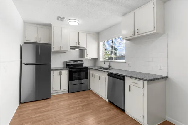 a kitchen with granite countertop a refrigerator and a sink