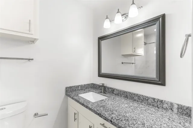 a bathroom with a granite countertop sink a mirror and a vanity