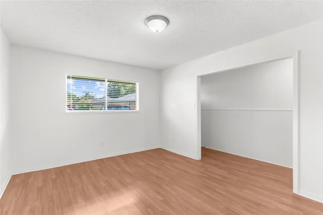 an empty room with wooden floor and window